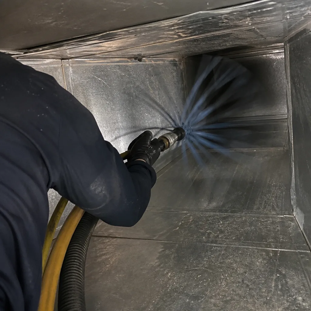 Technician using a rotating brush tool for professional air duct cleaning